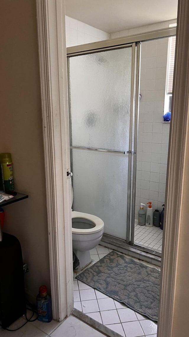 bathroom with tile patterned floors, toilet, and a shower stall