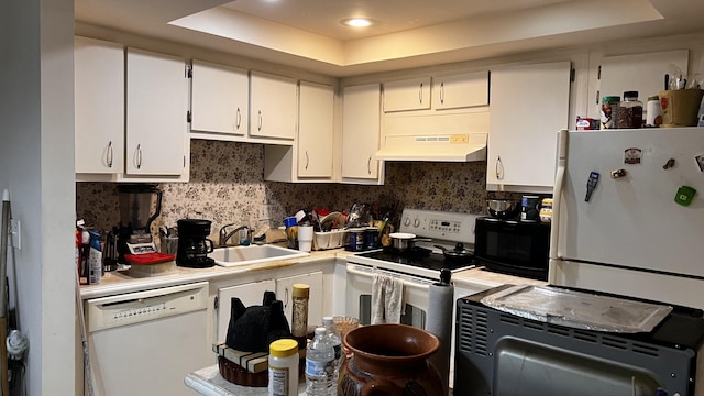 kitchen featuring under cabinet range hood, a sink, white appliances, white cabinets, and light countertops