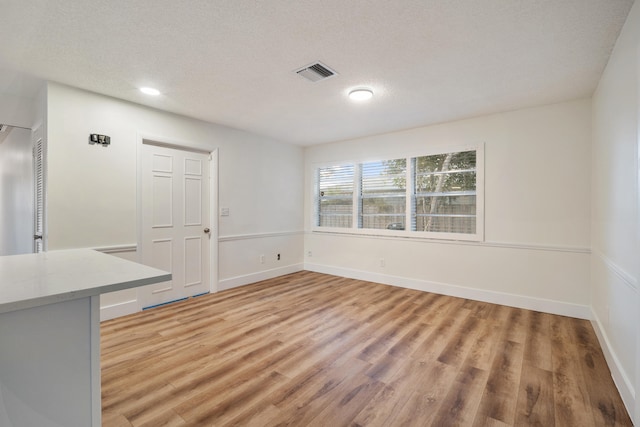 unfurnished dining area featuring wood-type flooring and a textured ceiling