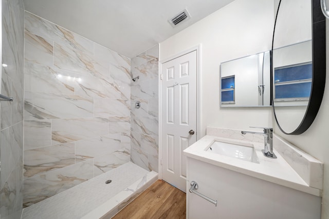 bathroom featuring tiled shower, vanity, and hardwood / wood-style flooring