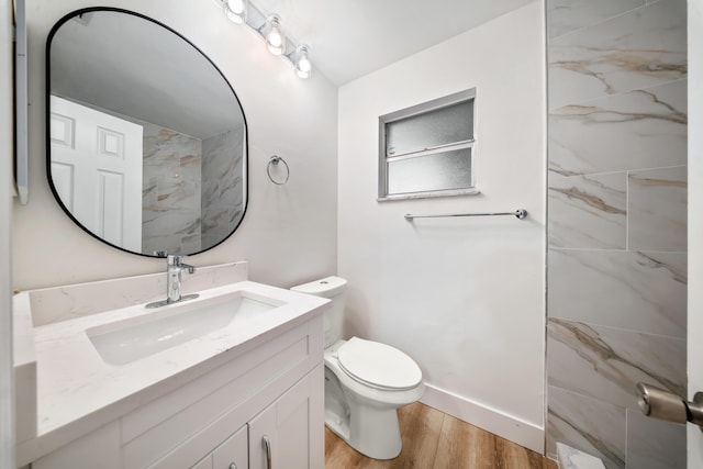 bathroom with tiled shower, vanity, hardwood / wood-style flooring, and toilet