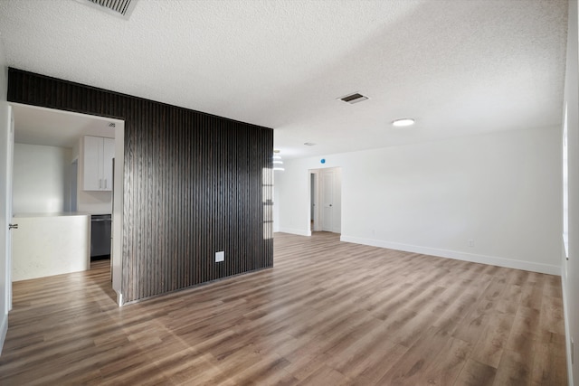 spare room featuring a textured ceiling and light hardwood / wood-style flooring