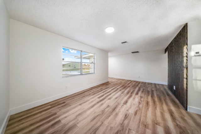 spare room with light wood-type flooring and a textured ceiling