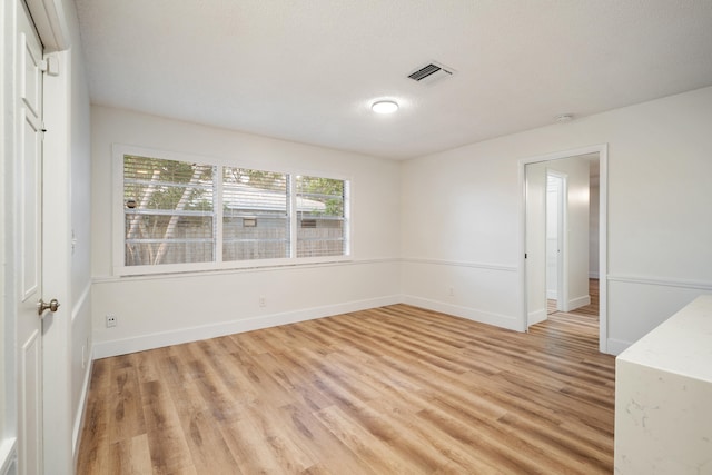 unfurnished room featuring light hardwood / wood-style floors and a textured ceiling