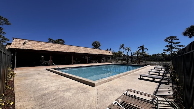 community pool with a patio and fence