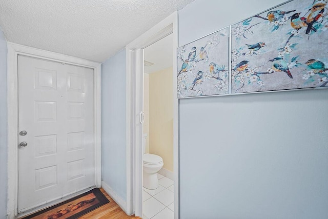 bathroom with toilet, wood-type flooring, and a textured ceiling