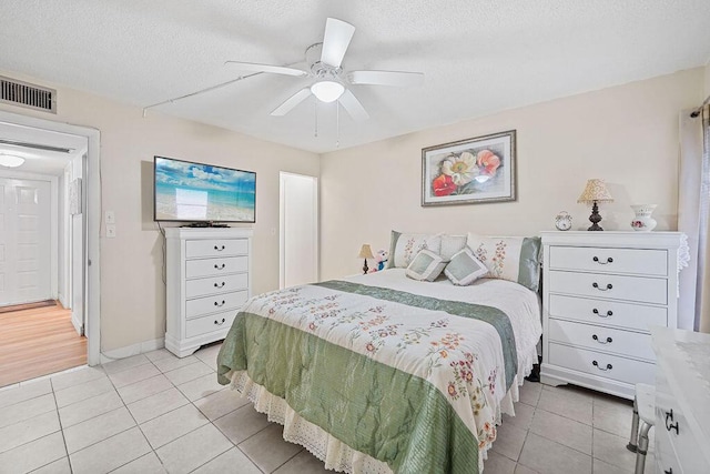 tiled bedroom featuring ceiling fan and a textured ceiling