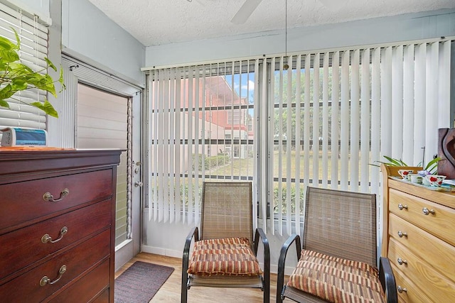 sitting room featuring ceiling fan, light hardwood / wood-style floors, and a textured ceiling