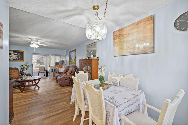 dining room with wood-type flooring, ceiling fan with notable chandelier, and a textured ceiling