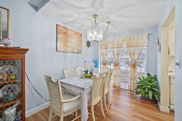 dining room with a chandelier, a textured ceiling, and light hardwood / wood-style flooring