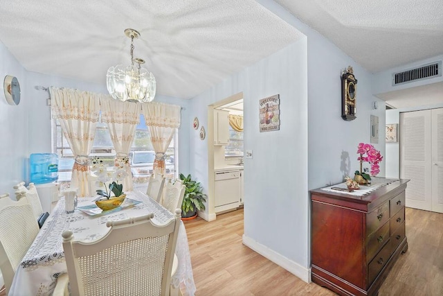 dining room featuring an inviting chandelier, a textured ceiling, and light wood-type flooring