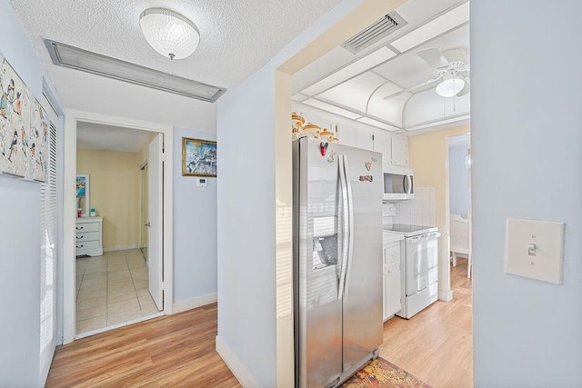 hall featuring a textured ceiling and light hardwood / wood-style flooring