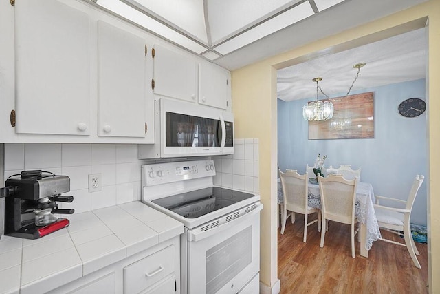 kitchen with white cabinetry, tile countertops, light hardwood / wood-style floors, white appliances, and decorative backsplash