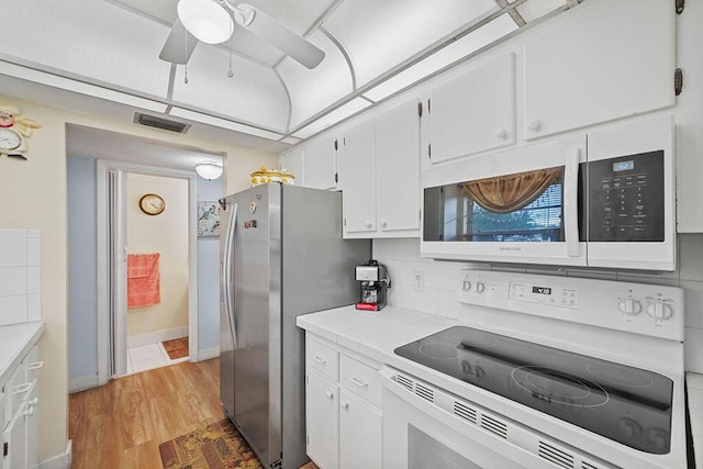 kitchen with white cabinetry, tile counters, backsplash, light hardwood / wood-style floors, and white appliances