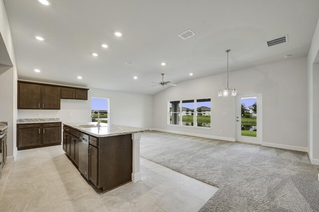 kitchen featuring sink, light stone counters, decorative light fixtures, light carpet, and ceiling fan with notable chandelier