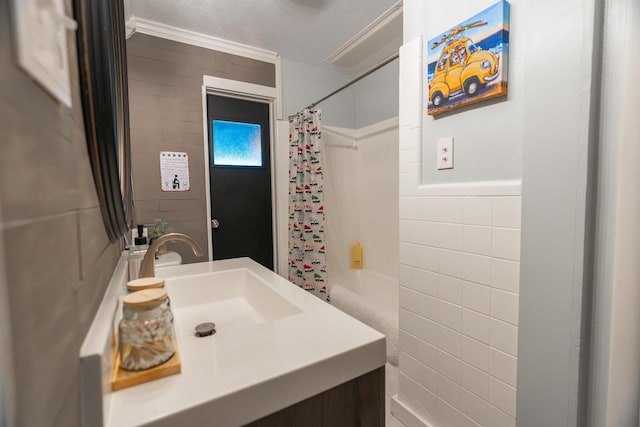 bathroom with shower / bathtub combination with curtain, sink, ornamental molding, and tile walls