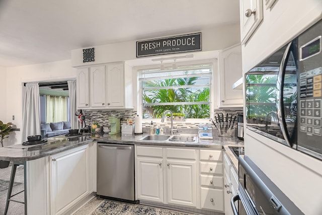 kitchen with tasteful backsplash, a breakfast bar, stainless steel appliances, sink, and white cabinets