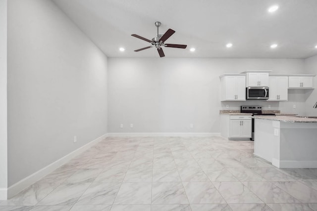 kitchen with appliances with stainless steel finishes, light stone counters, ceiling fan, sink, and white cabinets