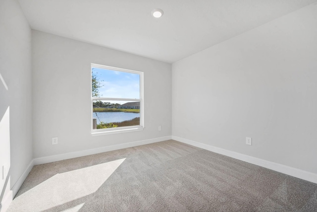 spare room with a water view and light carpet