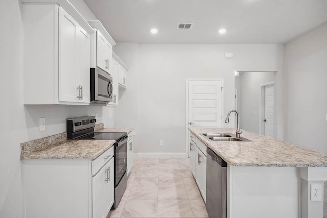 kitchen featuring appliances with stainless steel finishes, light stone counters, sink, a center island with sink, and white cabinets