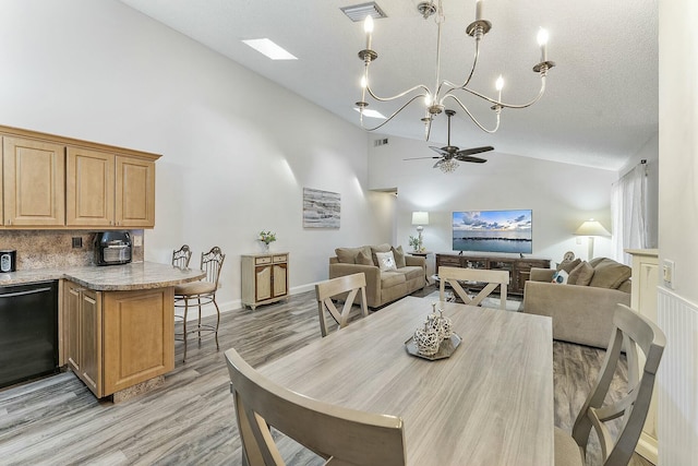 dining space with a textured ceiling, ceiling fan with notable chandelier, high vaulted ceiling, and light hardwood / wood-style flooring