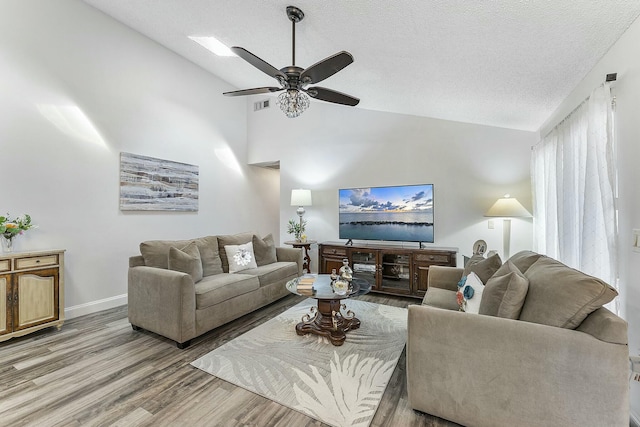 living room with lofted ceiling, ceiling fan, wood-type flooring, and a textured ceiling