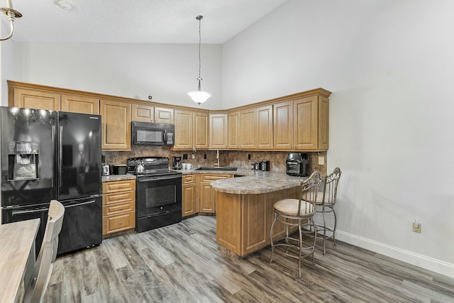 kitchen featuring backsplash, high vaulted ceiling, black appliances, hanging light fixtures, and kitchen peninsula