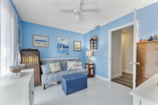 sitting room featuring a textured ceiling, light hardwood / wood-style flooring, and ceiling fan