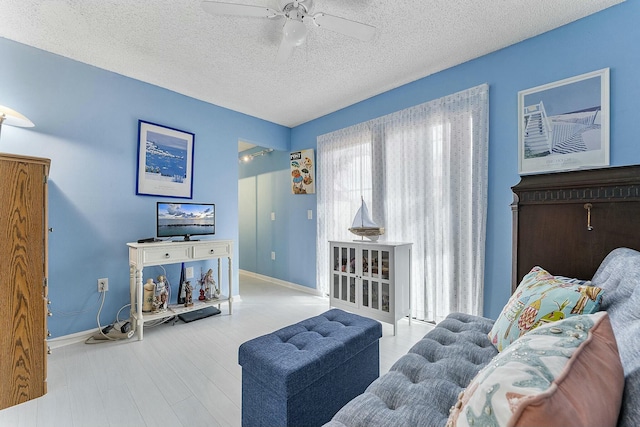 sitting room featuring ceiling fan, wood-type flooring, and a textured ceiling