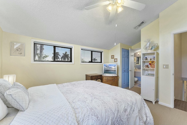 bedroom featuring ensuite bathroom, vaulted ceiling, ceiling fan, a textured ceiling, and light colored carpet