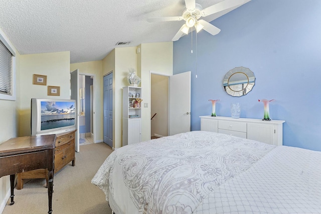 bedroom featuring light carpet, a textured ceiling, and ceiling fan