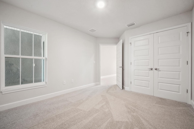 unfurnished bedroom with light carpet and a closet