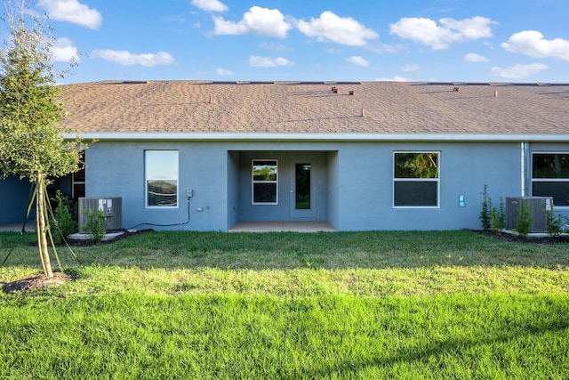 back of house featuring central AC unit and a lawn