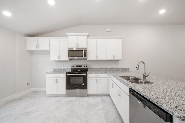 kitchen with white cabinets, appliances with stainless steel finishes, vaulted ceiling, and sink