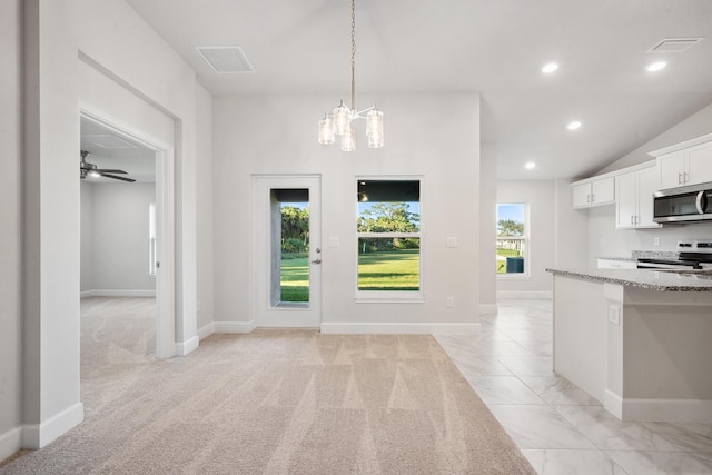 kitchen with electric range oven, light stone counters, light colored carpet, decorative light fixtures, and white cabinets