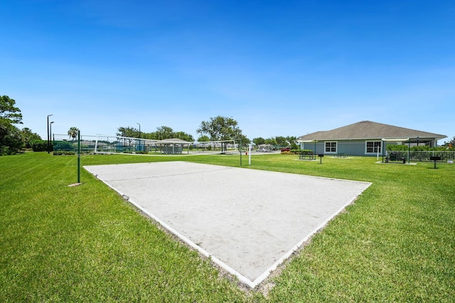 view of property's community featuring a yard, fence, and volleyball court