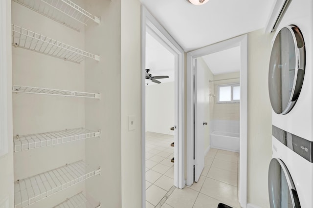 clothes washing area with ceiling fan, light tile patterned floors, and stacked washing maching and dryer