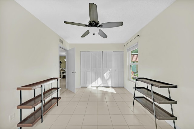 tiled entryway featuring a textured ceiling and ceiling fan