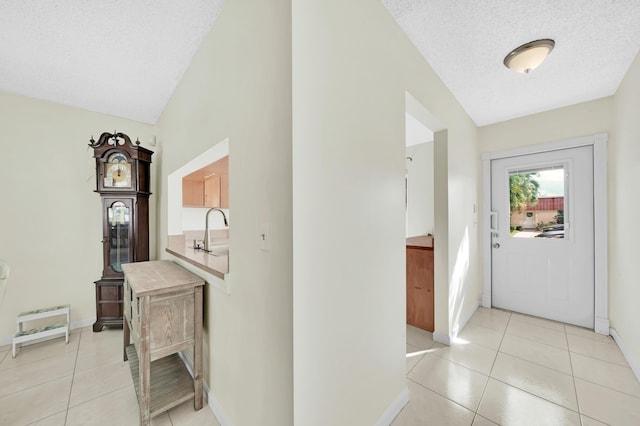 hallway featuring light tile patterned floors, a textured ceiling, and sink