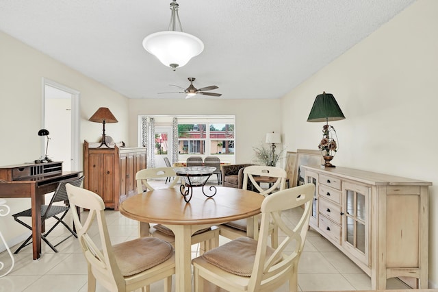 tiled dining area with ceiling fan and a textured ceiling