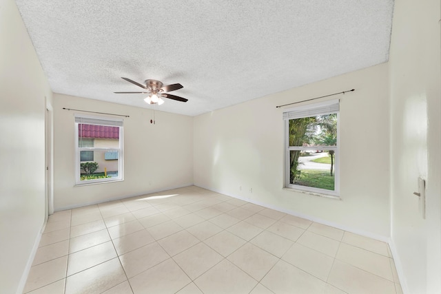 spare room featuring ceiling fan, light tile patterned floors, and a textured ceiling