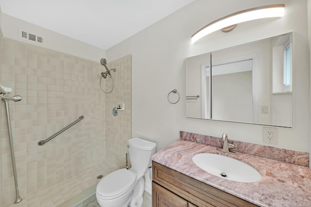 bathroom with tiled shower, vanity, and toilet