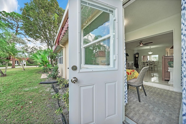 view of exterior entry featuring a yard and ceiling fan