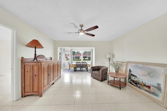 tiled living room with ceiling fan and a textured ceiling