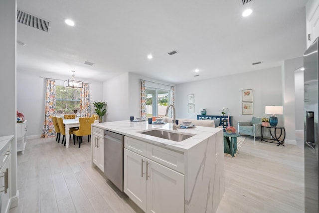 kitchen featuring dishwasher, light hardwood / wood-style floors, white cabinetry, and a kitchen island with sink