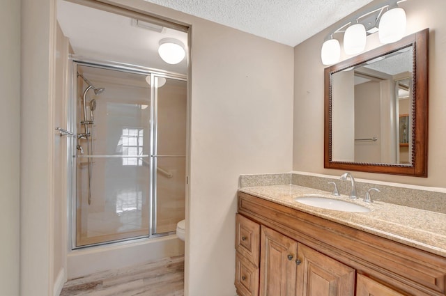 bathroom featuring vanity, hardwood / wood-style flooring, toilet, a textured ceiling, and walk in shower