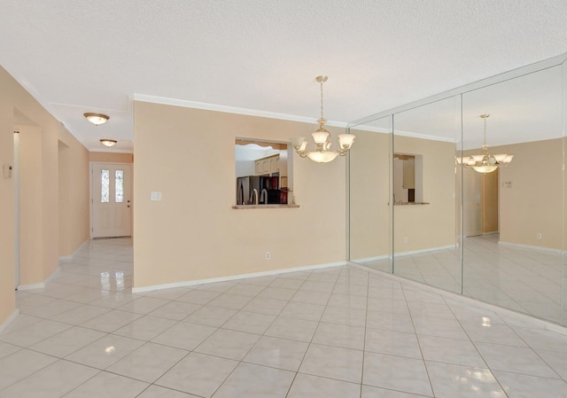 tiled spare room with ornamental molding, a textured ceiling, and a chandelier