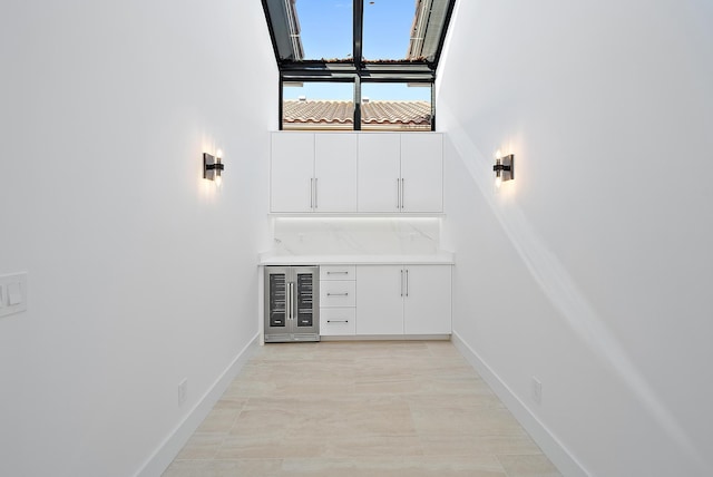 bar with white cabinetry and beverage cooler