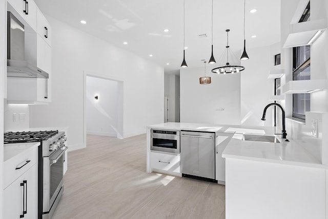 kitchen featuring stainless steel appliances, ventilation hood, sink, decorative light fixtures, and white cabinetry