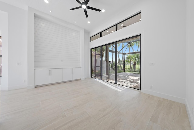 spare room with light tile patterned floors, a towering ceiling, and ceiling fan